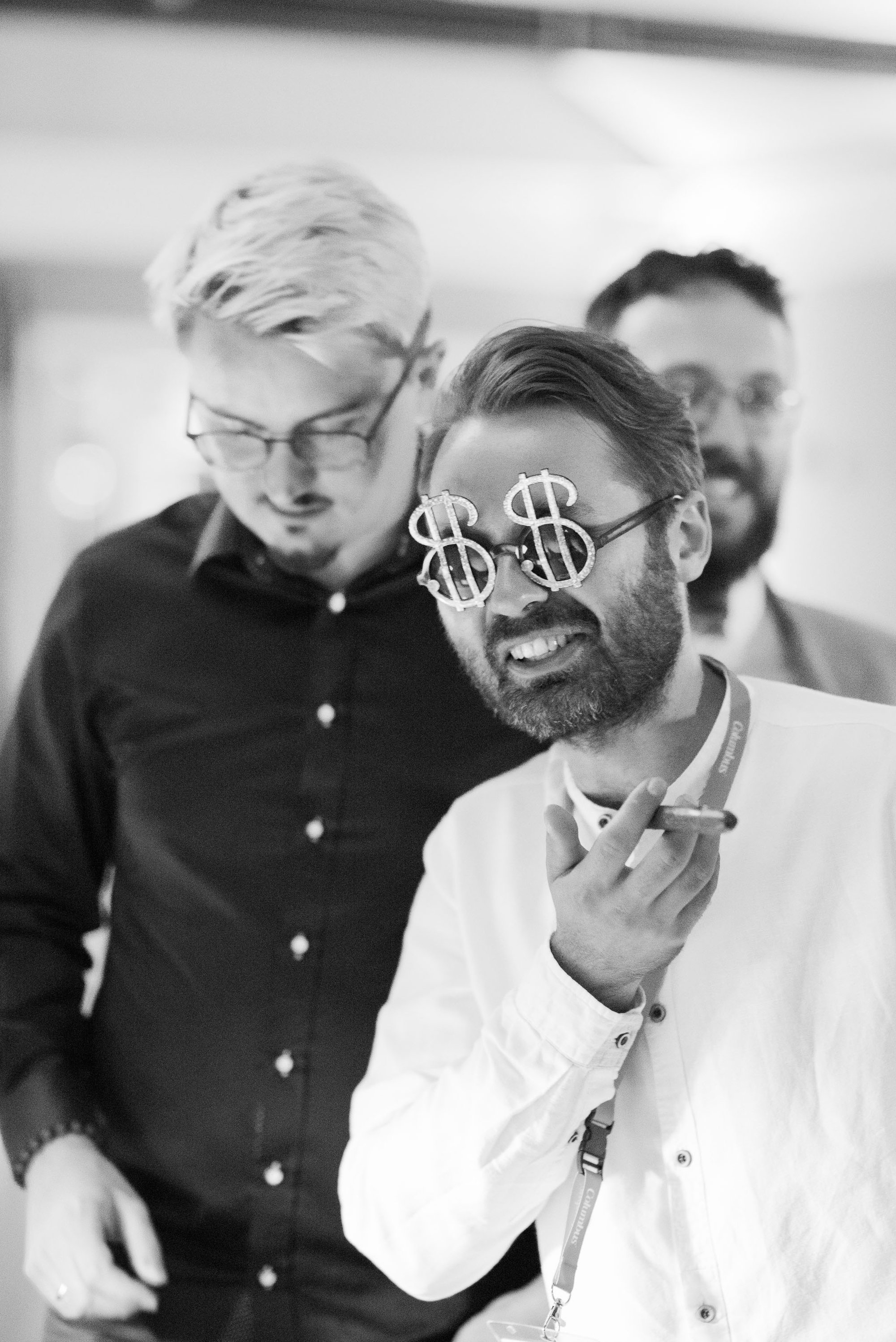 Man posing to a picture wearing glasses with dolar sign